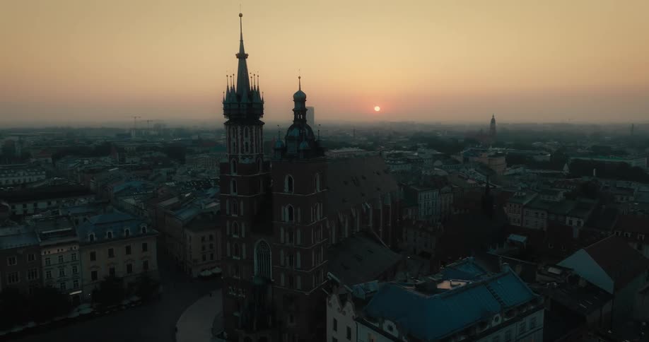 Aerial view of a downtown city while the sun is setting behind a gothic cathedral