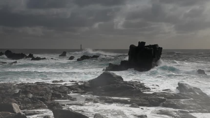 Waves are lashing a rocky shoreline on a stormy day