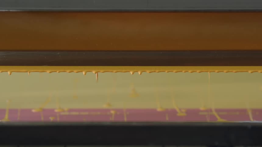 A line of wet yellow paint is dripping down