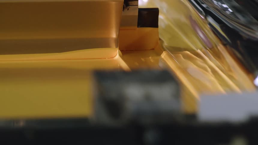 Close up of yellow ink being evenly spread on a machine in a factory