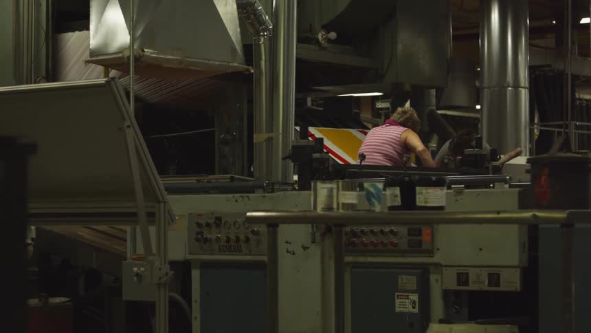 A woman is working in a factory near a conveyor belt