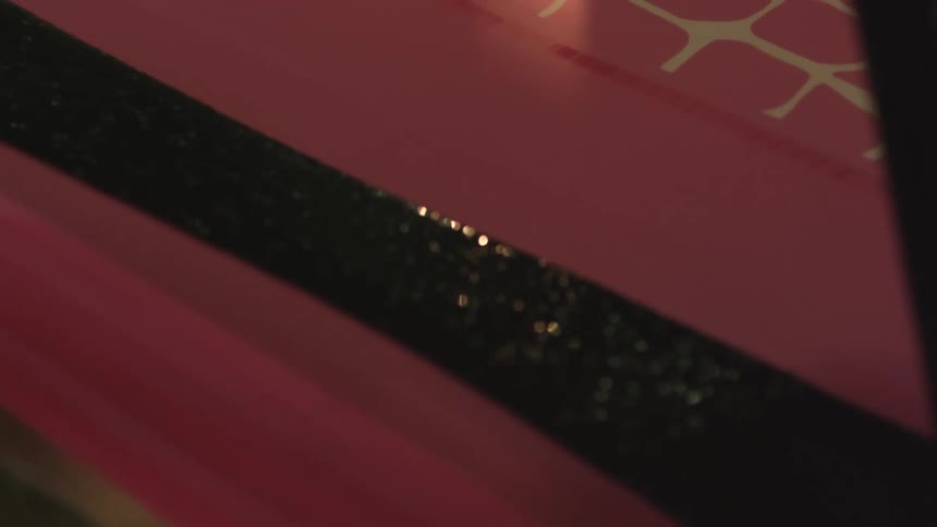 Black paint being poured on pink cloth