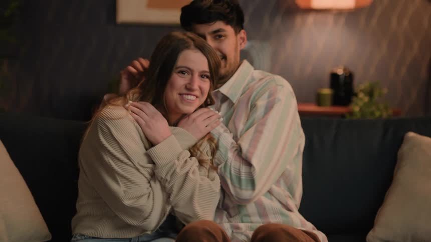 A young couple is hanging out and sitting on the couch