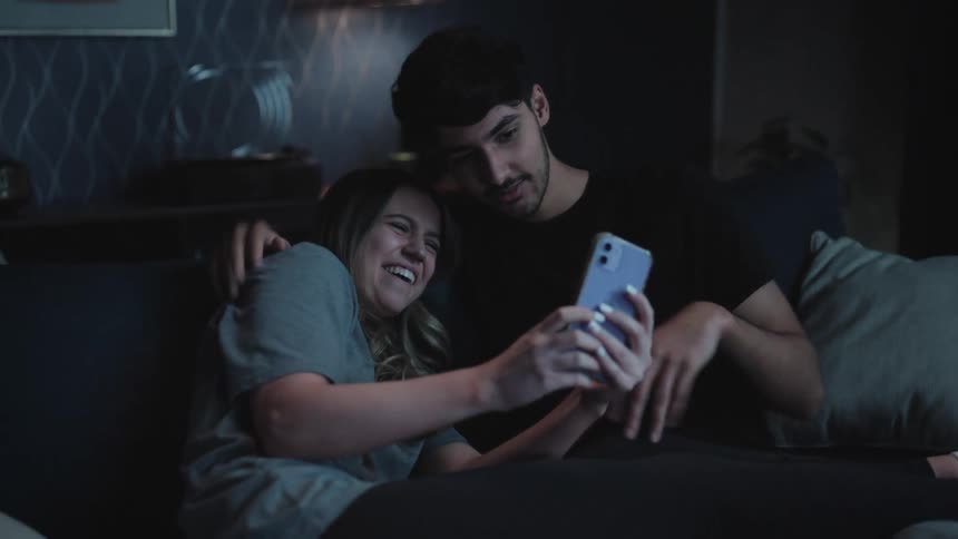 Young happy couple reclined on the couch at home make funny faces for a photo