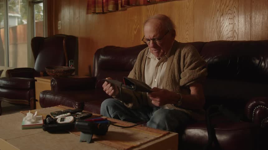 An older elderly man is sitting down and taking his blood pressure