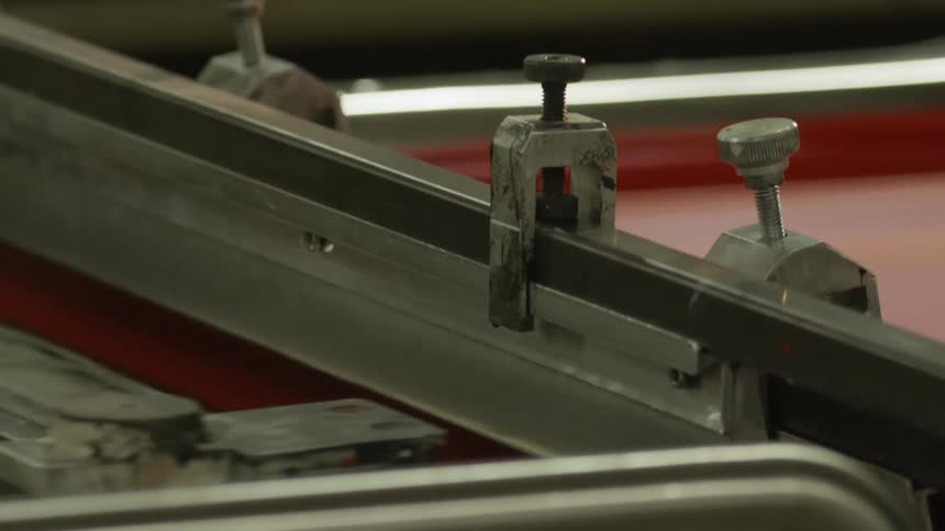 A factory machine moves and paint drips when the arm is raised