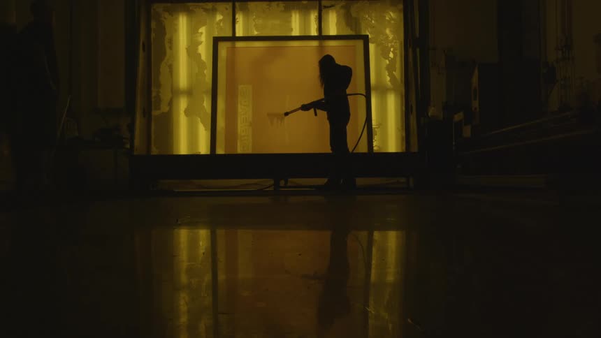 Worker wearing a full body protective suit sprais a room using a power washing machine