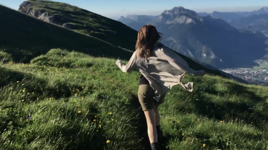 A woman runs along the grass on a mountain