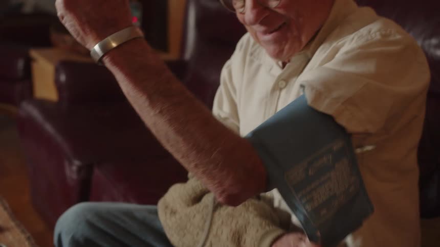 An old elderly man is taking his blood pressure indoors