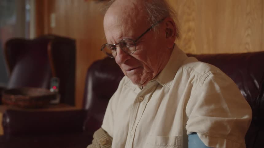 An older elderly man is sitting on a couch indoors