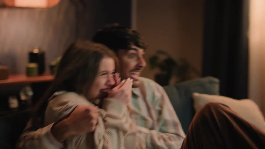 Young couple is sitting on the couch and watching tv