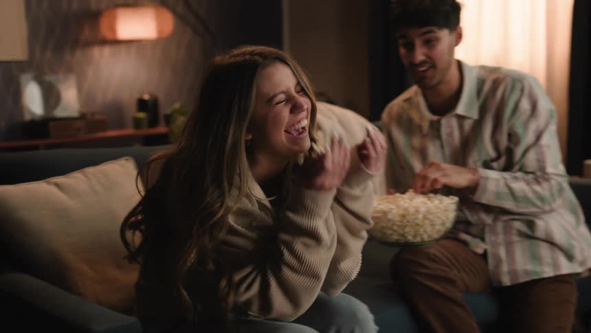 Young couple is sitting down and eating some popcorn