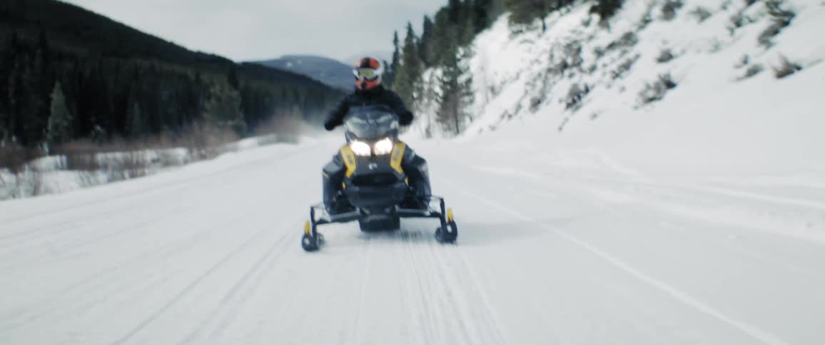 People are snow mobiling outdoors in the winter time