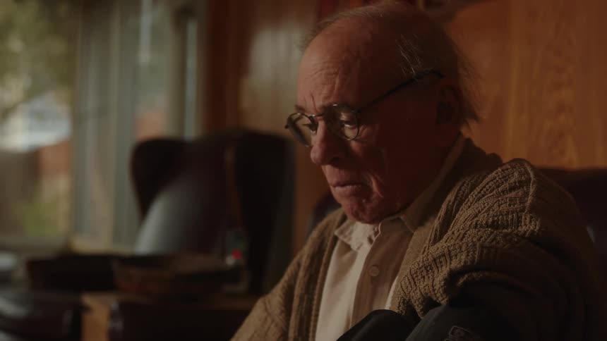 Close up of the face of an elderly man sitting on the couch at home feeling uncomfortable
