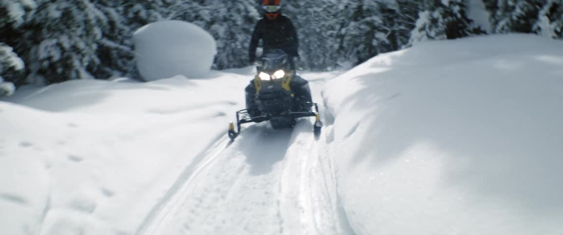 A person drives their snowmobile through the woods