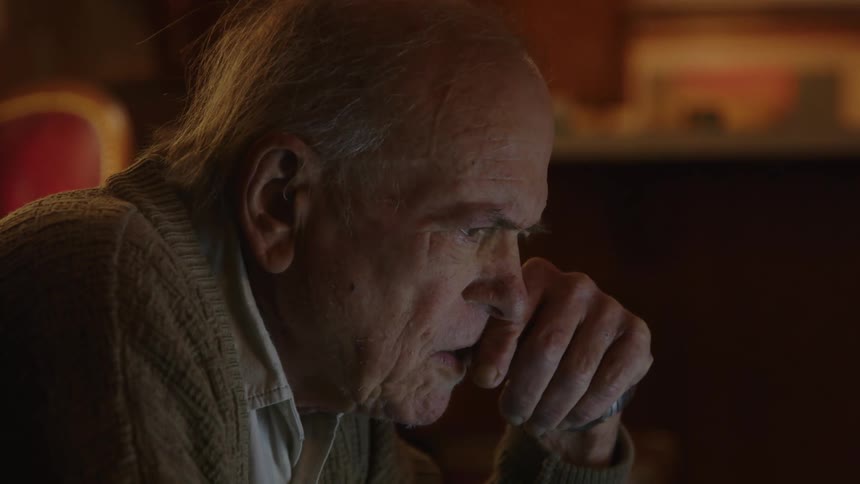 An older elderly man is sitting down on a couch