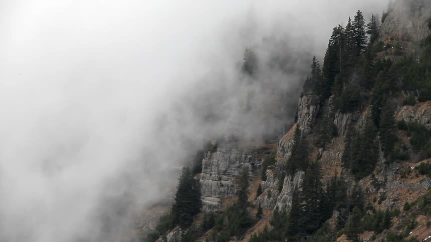 Clouds pour down the side of a mountain