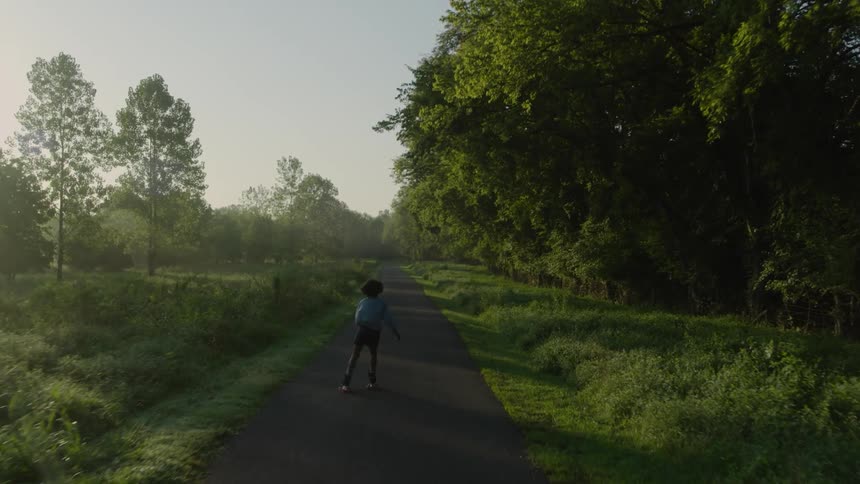 A young kid is rollerblading around the forest area in the day time