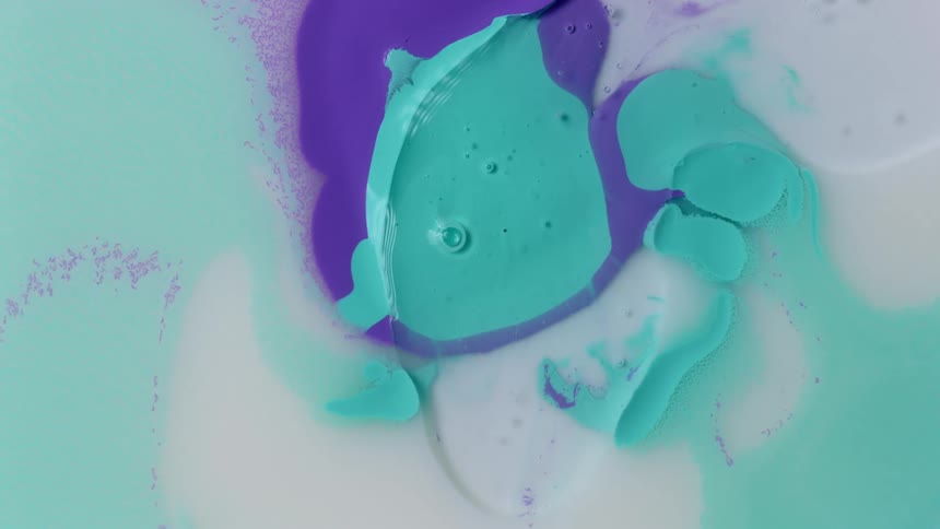 Colored liquid moves as purple is beginning to mix with green