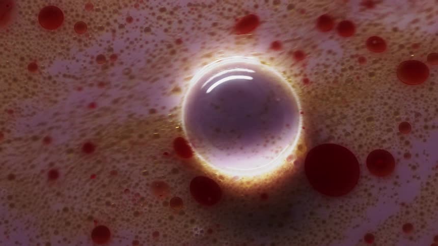 A pink liquid with red spots moves among bubbles on the surface