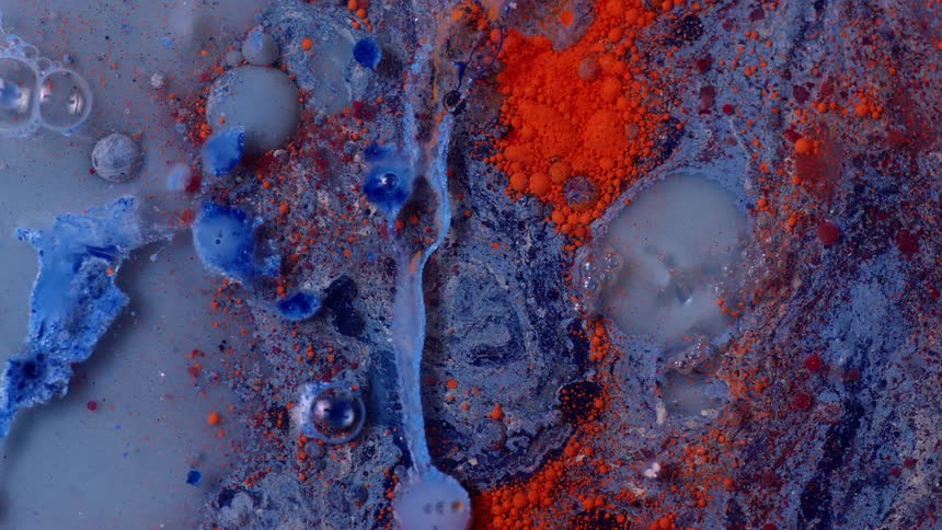Red areas are splattered on an organic blue surface that is moving and bubbling as it spreads
