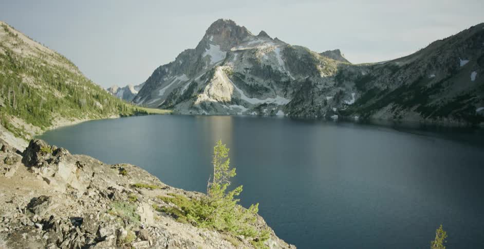 Aerial view of mountains near a body of water is displayed