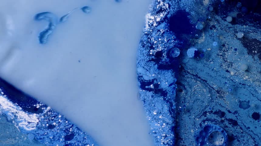 Blue liquid paint being swirled around and mixed with soapy liquid