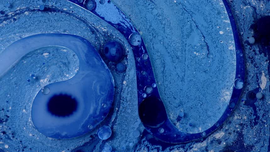 Bubbles float on surface as different shades of blue swirl in mixture