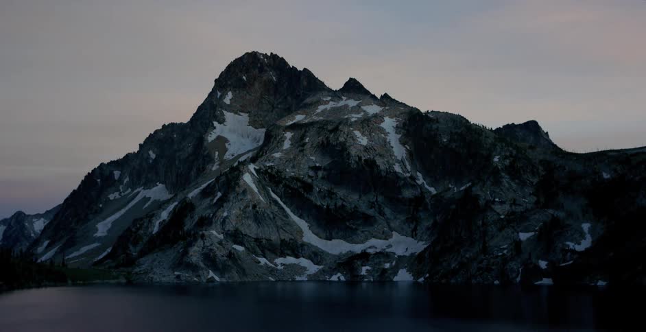 Sunrise begins at a high lake with a tall mountain behind it