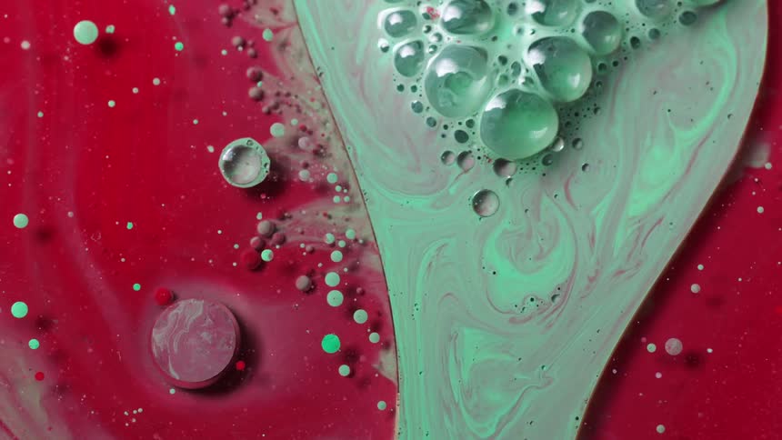 A green bubbling liquid is moving over a red spotted area