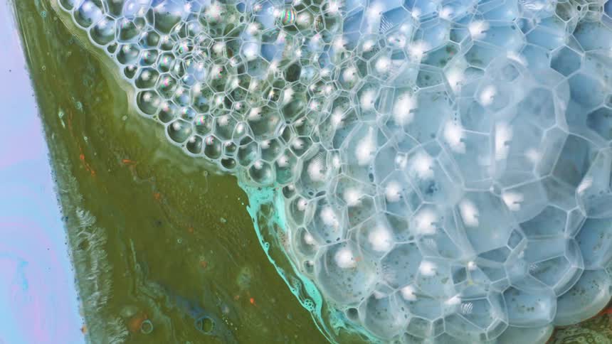 Bubbles form on the surface of a creamy blue and green liquid
