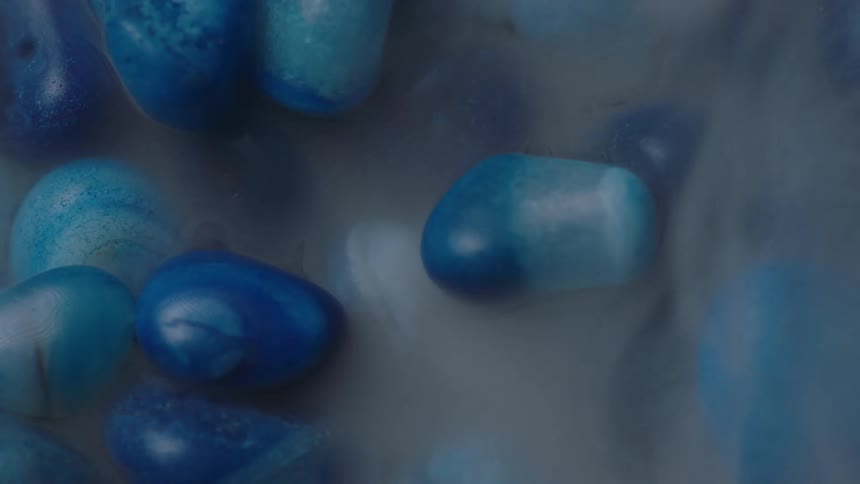 White smoke wavers and moves to expose blue polished stones lying on the ground