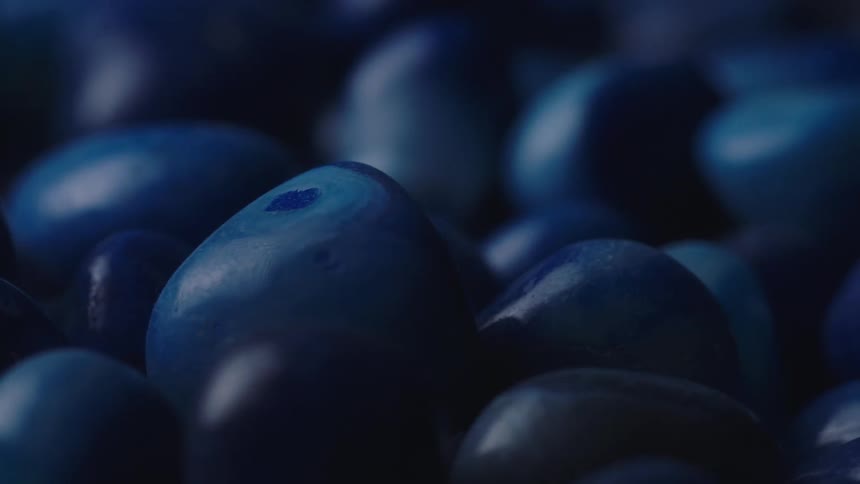 Numerous blue smooth and colorful stones with are piled together