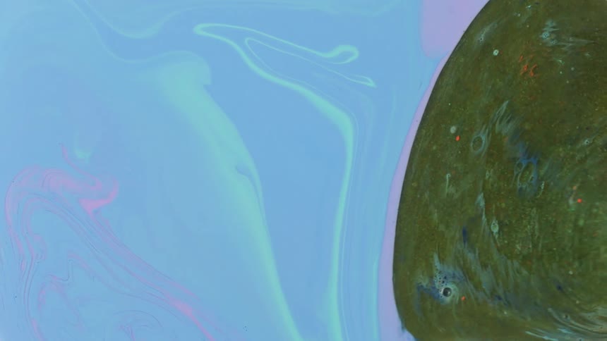 Green blob of liquid ink expanding and pushing out blue liquid ink