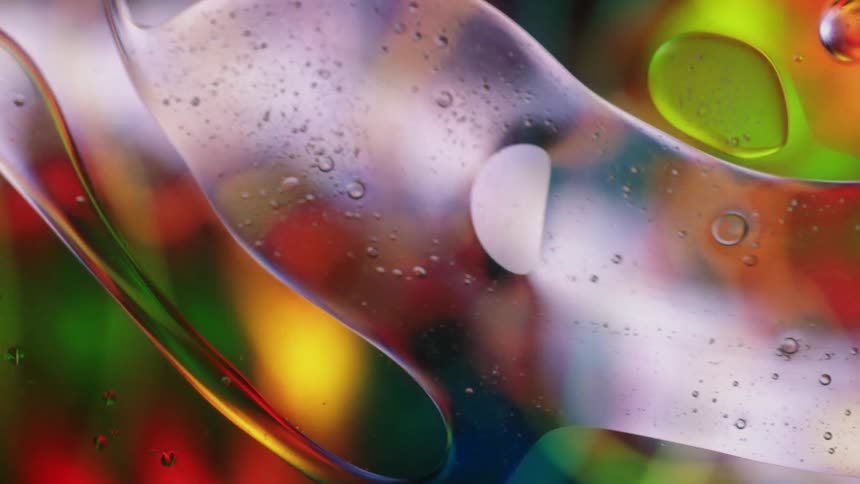 Colored lights glow in the distance as thick clear liquid containing bubbles moves and reflects the colors