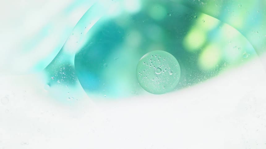 A liquid with bubble filled droplets suddenly has a bright light cast upon it