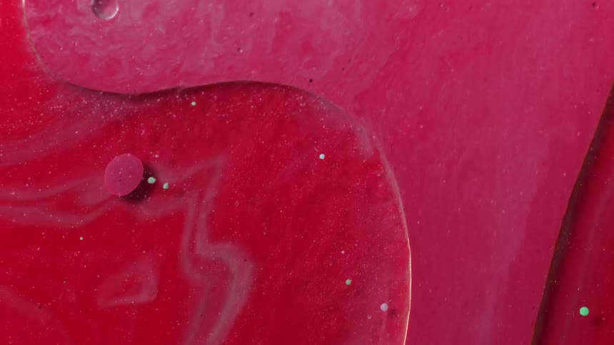 Time lapse close up of streams of red and pink liquid in bubbling while flowing