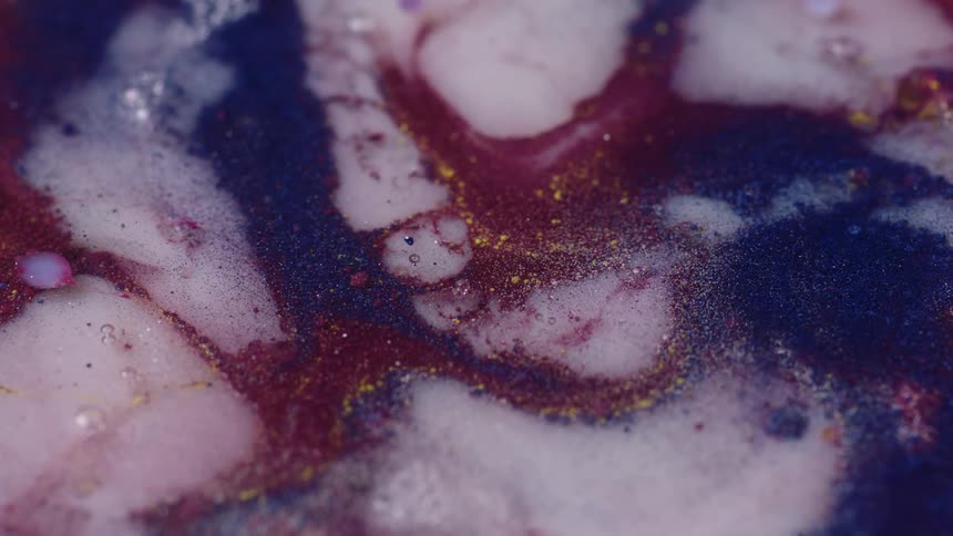A number of colorful liquids with glitter suspended in it gradually swirl around