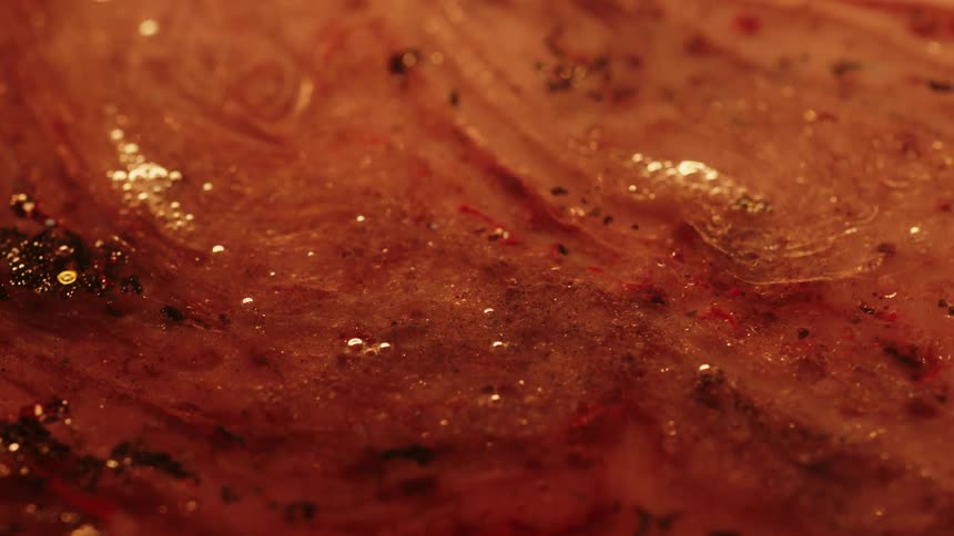 A closeup shows a colorful liquid with glitter suspended in it swirling gently