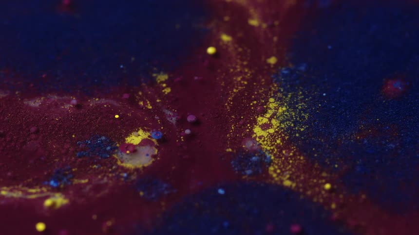 Yellow specks of liquid ink sprinkled over a surface of dark inks