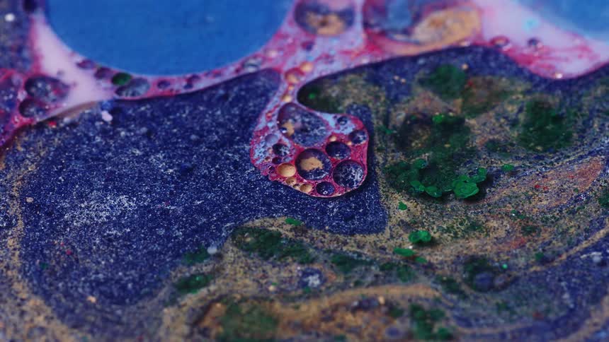 An up close of liquid paint in all different colors with bubbles in it