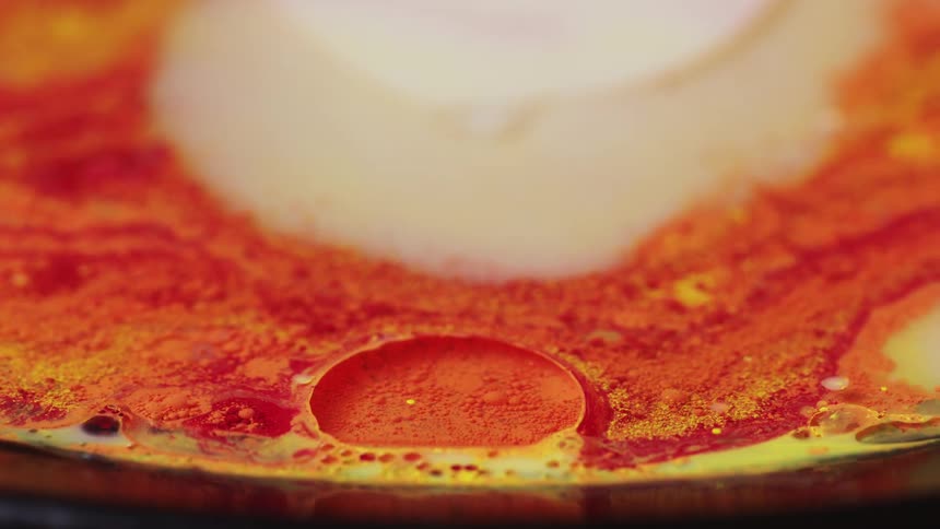 An orange hued liquid settles as bubbles have risen to its surface