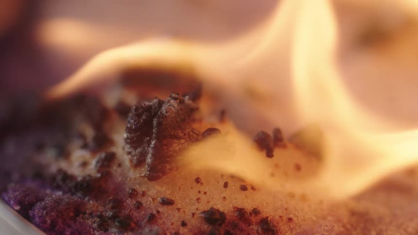 Flames waver and move as a charred substance bubbles and burns