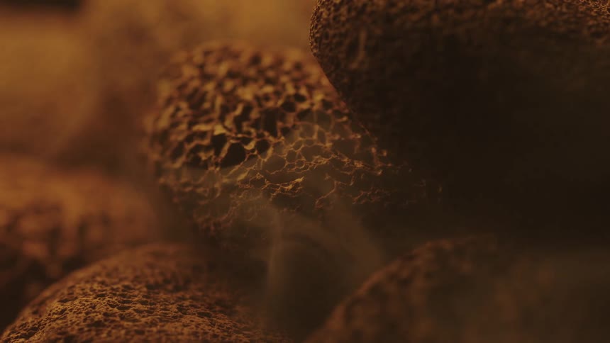 Extreme close up of dust flowing from and around small brown sponge like pebbles