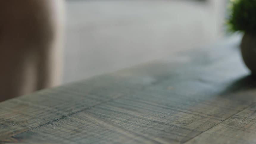 A white game controller on a table being picked up by a person