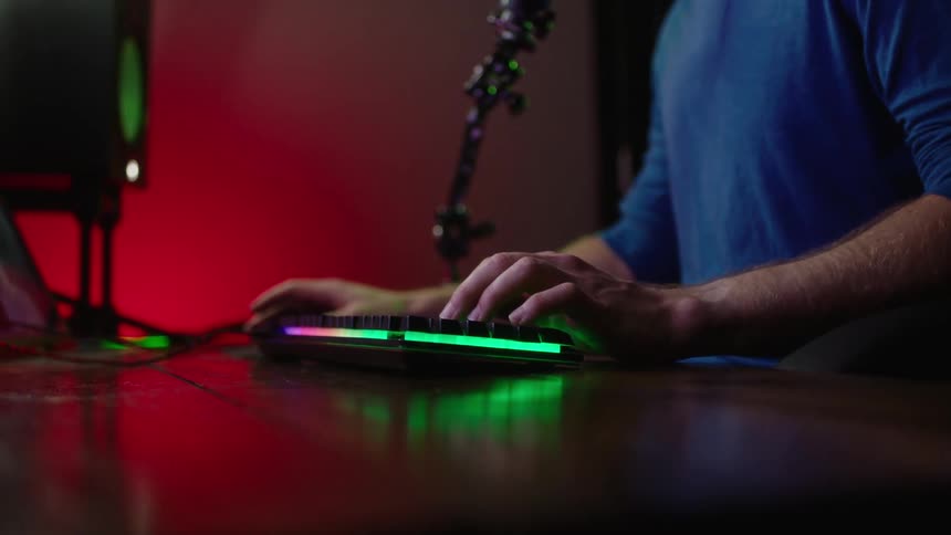 A person using their keyboard on their desk with a multicolor light display