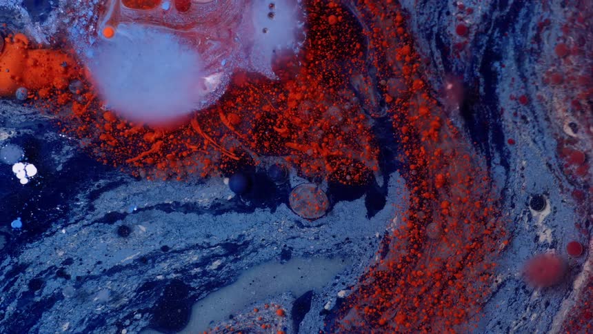 Abstract closeup of red blue and white paints with powders and oil all swirled together