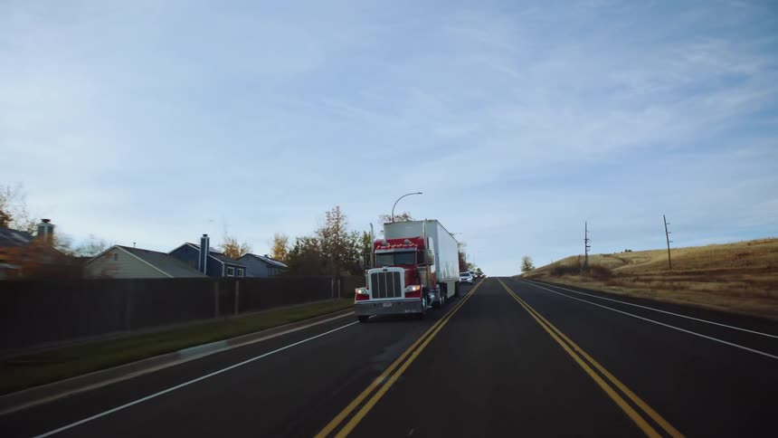A semitruck 18wheeler traveling on a highway during the day