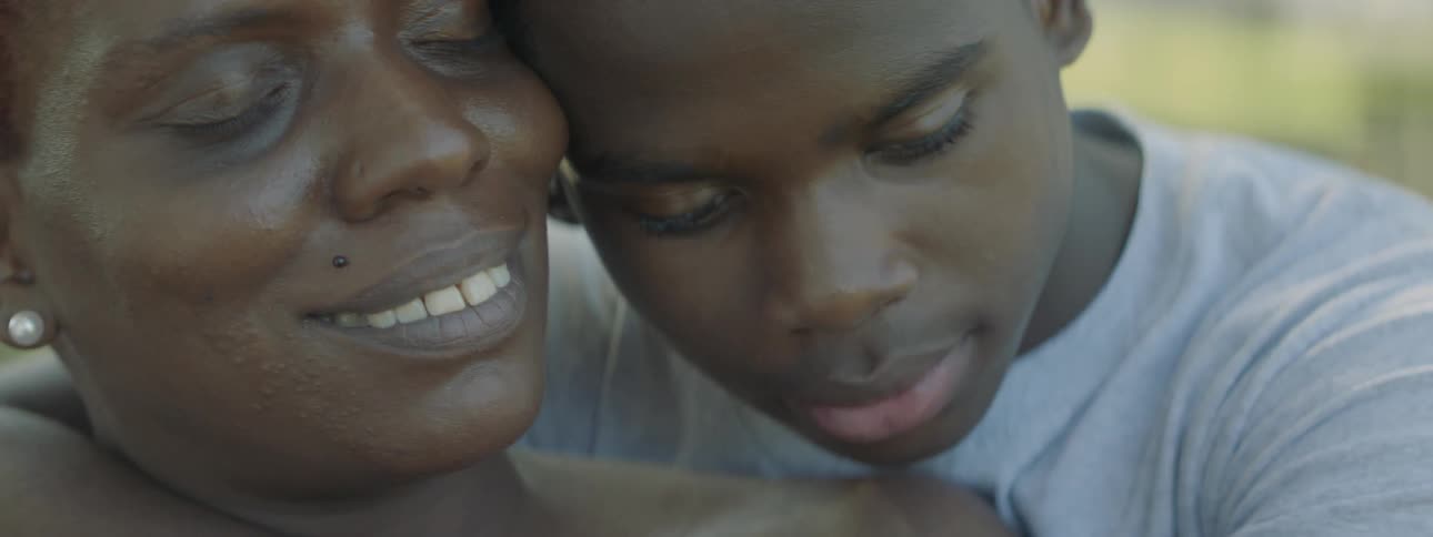 A boy leans his head against a woman as she smiles