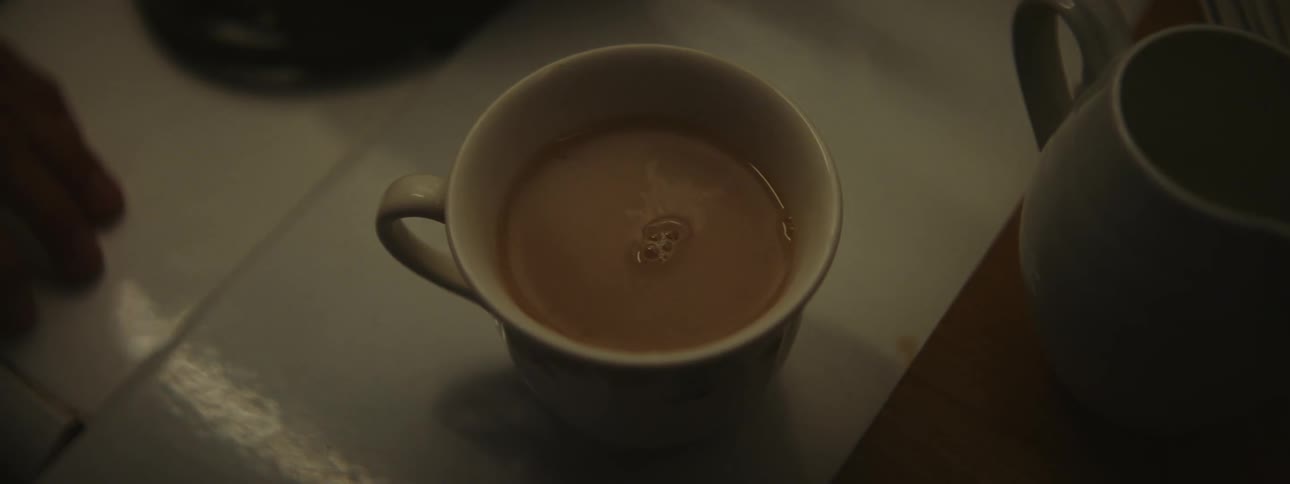 A woman adds cream to coffee and stirs it